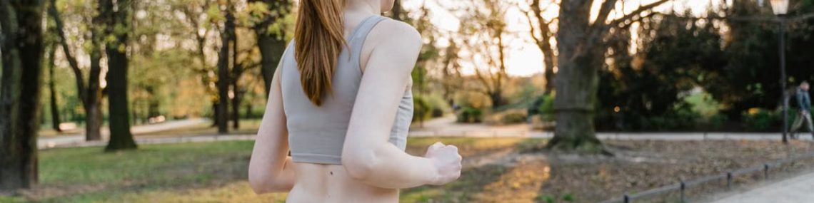 A woman jogs in a park during sunset, enjoying an outdoor fitness routine.